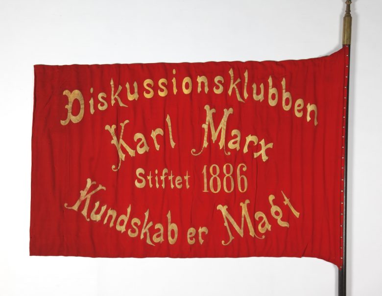 Fane for Diskussionsklubben Karl Marx. Påskrevet står “Kundskab er Magt” 